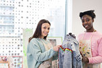 Portrait smiling teenage girls designing denim jacket in fashion design class