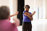 Smiling active senior stretching arm in exercise class