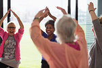 Happy active senior women exercising, stretching arms overhead in exercise class