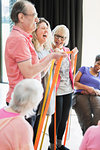 Smiling active seniors and instructor stretching, exercising with straps