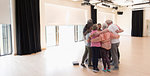 Active seniors bonding, hugging in circle in exercise studio