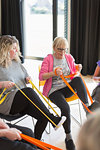 Active senior woman exercising, stretching leg with strap in exercise class