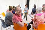 Portrait happy active senior man meeting with group in circle in community center