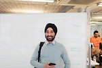 Portrait smiling, confident Indian businessman in turban standing at whiteboard in office