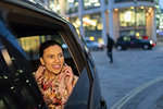 Smiling businesswoman talking on smart phone in crowdsourced taxi at night