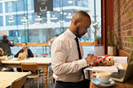 Businessman using smart phone and eating lunch in cafe