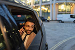 Businessman talking on smart phone in crowdsourced taxi