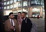 Business people with smart phone talking on city street at night