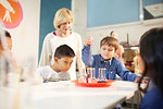 Teacher and students using pipette and beakers at interactive exhibit in science center