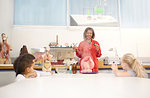 Science teacher and curious students with anatomical models