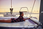 Serene young woman relaxing on catamaran net at sunset