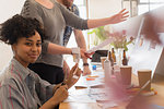 Portrait confident creative designer cutting photographs in office