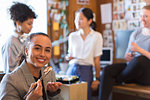 Portrait smiling, confident creative businesswoman eating sushi in office