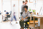 Serene woman meditating with headphones in office