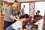 Creative businesswoman receiving massage from masseuse in office