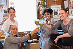 Portrait confident creative female designers drinking green smoothies in office