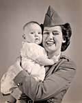 1940s SMILING WOMAN MOTHER WEARING ARMY UNIFORM LOOKING AT CAMERA HOLDING BABY