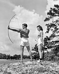 1930s TEENAGE COUPLE PRACTICING ARCHERY SHOOTING BOW AND ARROW