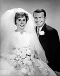 1960s PORTRAIT OF HAPPY SMILING BRIDE AND GROOM IN WEDDING CLOTHES LOOKING AT CAMERA