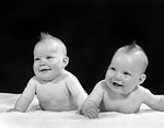 1950s TWO TWIN BABIES SMILING LYING ON THEIR STOMACHS LOOKING UP