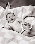 1920s HAPPY BABY POSED LYING ON SIDE WEARING CLOTH DIAPER TOY DOG ABOVE HER HEAD