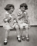 1920s TWO LITTLE GIRLS SITTING ON BENCH EATING ICE CREAM CONES AND TALKING