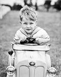 1930s BOY IN SAILOR SUIT DRIVING RACING TOY PEDDLE CAR LOOKING AT CAMERA HUGGING THE STEERING WHEEL WITH BOTH HANDS