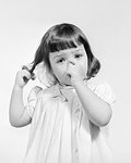 1950s 1960s UNHAPPY LITTLE GIRL SUCKING HER THUMB TWIRLING HER HAIR LOOKING AT CAMERA