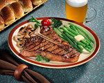 1950s AMERICAN FARE GRILLED T-BONE STEAK ON PLATE WITH GREEN BEANS AND MUSHROOMS ALONG WITH GLASS OF BEER AND DINNER ROLLS