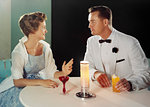 1950s 1960s MAN WOMAN FORMAL ATTIRE SITTING TABLE TALKING HAVING COCKTAILS