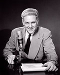 1950s SMILING MIDDLE AGED MAN NEWSMAN ANNOUNCER  TALKING INTO MICROPHONE LOOKING AT CAMERA