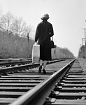 1950s 1960s BATTERED WOMAN ESCAPING BACK TO CAMERA WALKING DOWN RAILROAD TRACKS CARRYING SUITCASE LEAVING