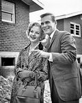 1950s 1960s SMILING COUPLE POINTing TO NEW BRICK HOUSE UNDER CONSTRUCTION