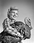 1950s SMILING BLOND WOMAN WEARING PLAID SHIRT HOLDING A BIG TOM TURKEY