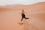 Woman running in desert, Douba, Morocco