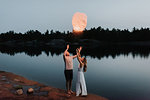 Couple releasing sky lanterns by lake, Algonquin Park, Canada