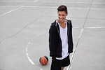 Male teenage basketball player on basketball court, smiling