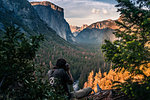 Rock climber taking photograph of mountain ranges, Yosemite National Park, California, USA