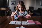 Girl with stack of gambling chips playing cards at table, portrait