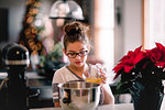 Girl pouring egg yolk into mixing bowl for christmas cookies at kitchen counter