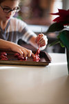 Girl placing christmas cookie dough onto baking tray at kitchen counter