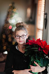 Girl holding christmas poinsettia in living room, portrait