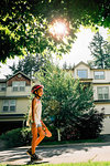 Tween Girl Walking on Sidewalk Carrying Skateboard in Residential Neighborhood