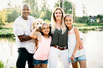 Portrait of mixed-race family by lake with labradoodle puppy