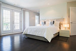 Master bedroom with queen size bed and dark wooden flooring, upstairs inside luxury residential home