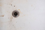 High angle close up of dirty drain in stained old bathtub.