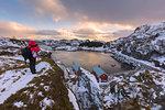 Photographer on rocky peak, Nusfjord, Lofoten Islands, Nordland, Norway, Europe