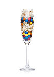 Popcorn and round chocolate candies in glass on white background