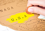 Travel holiday to United States of America concept with female hand scratching map choosing USA