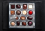 Assortment of luxury white and dark chocolate candies variety in silver plastick tray on black stone background